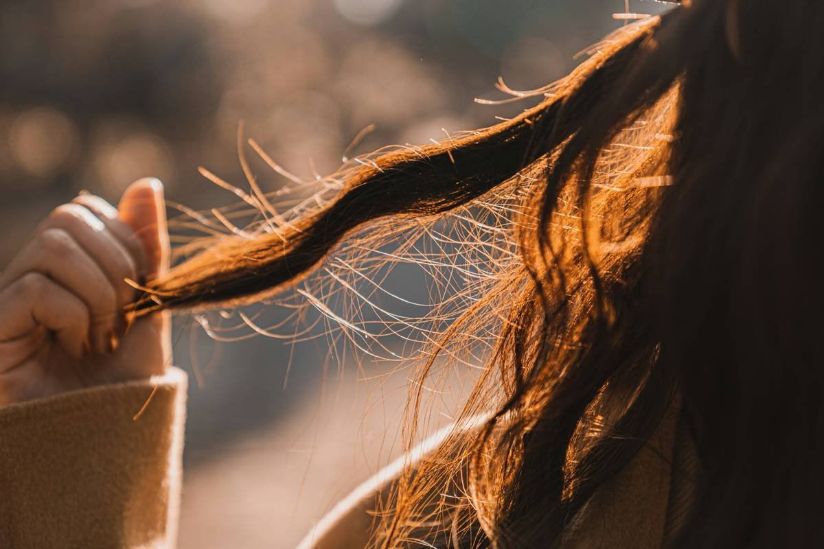 Woman applying hair treatment lotion to damp curls for deep hydration
