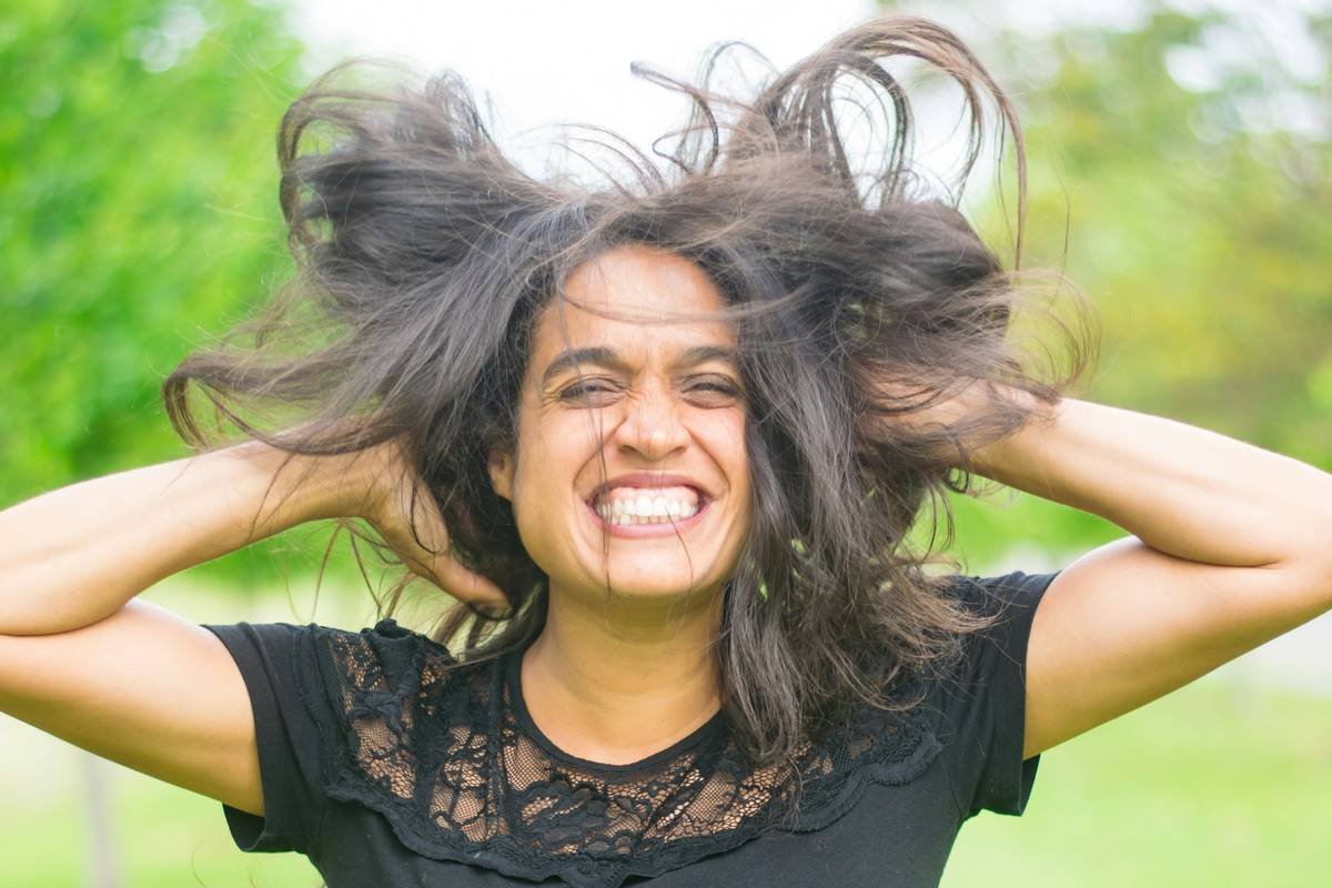Woman applying hair body enhancer spray at roots for volume