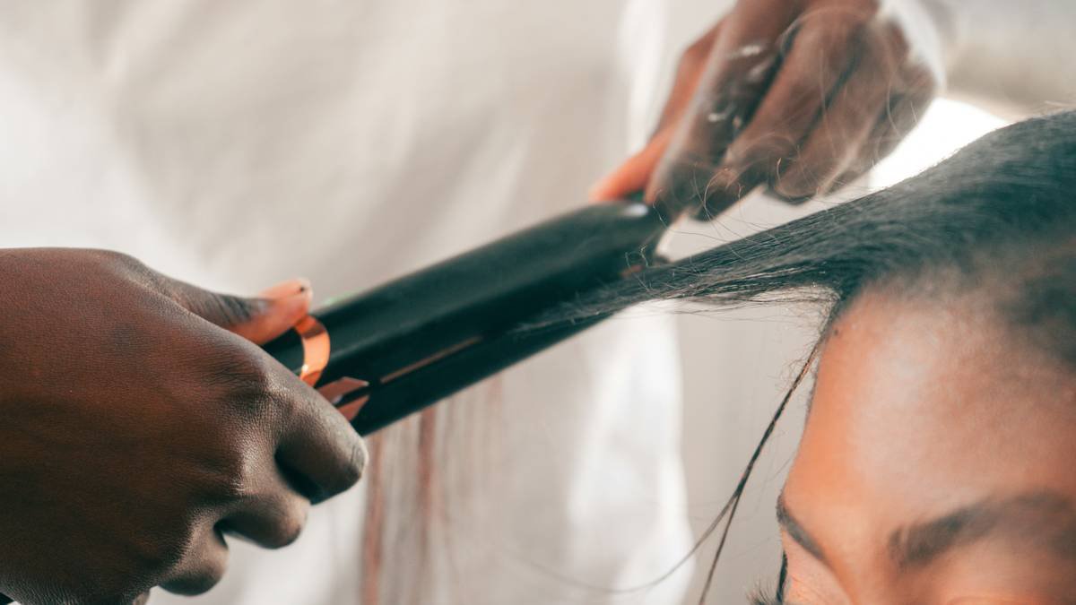 Woman applying texturizing spritz to shoulder-length wavy hair for added volume and separation