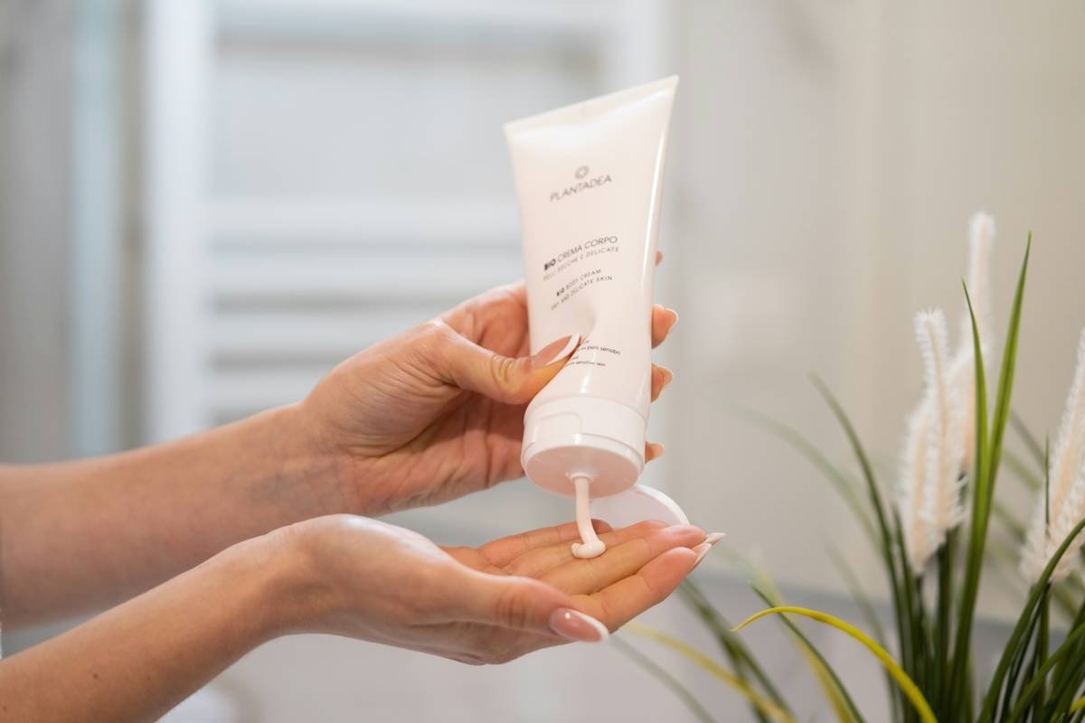 Close-up of hands applying hair styling cream to textured, wavy hair
