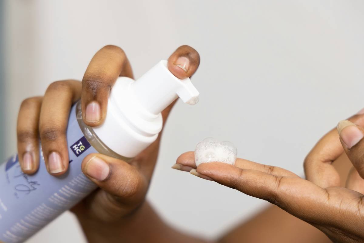 Woman applying volumizing foam to damp hair roots for volume and body